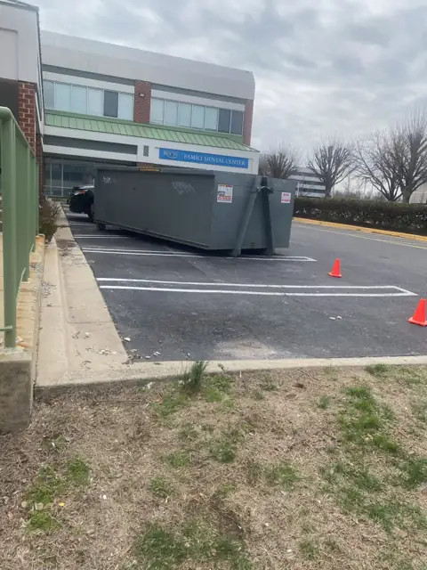 Roll off container in a commercial parking lot in Gaithersburg, MD, with cones marking the spot