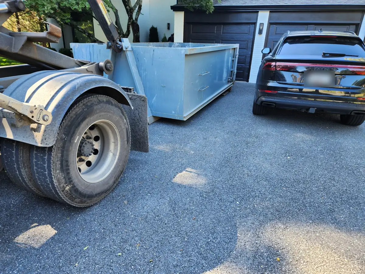 Roll off container being placed on a dark gravel driveway in Potomac, MD