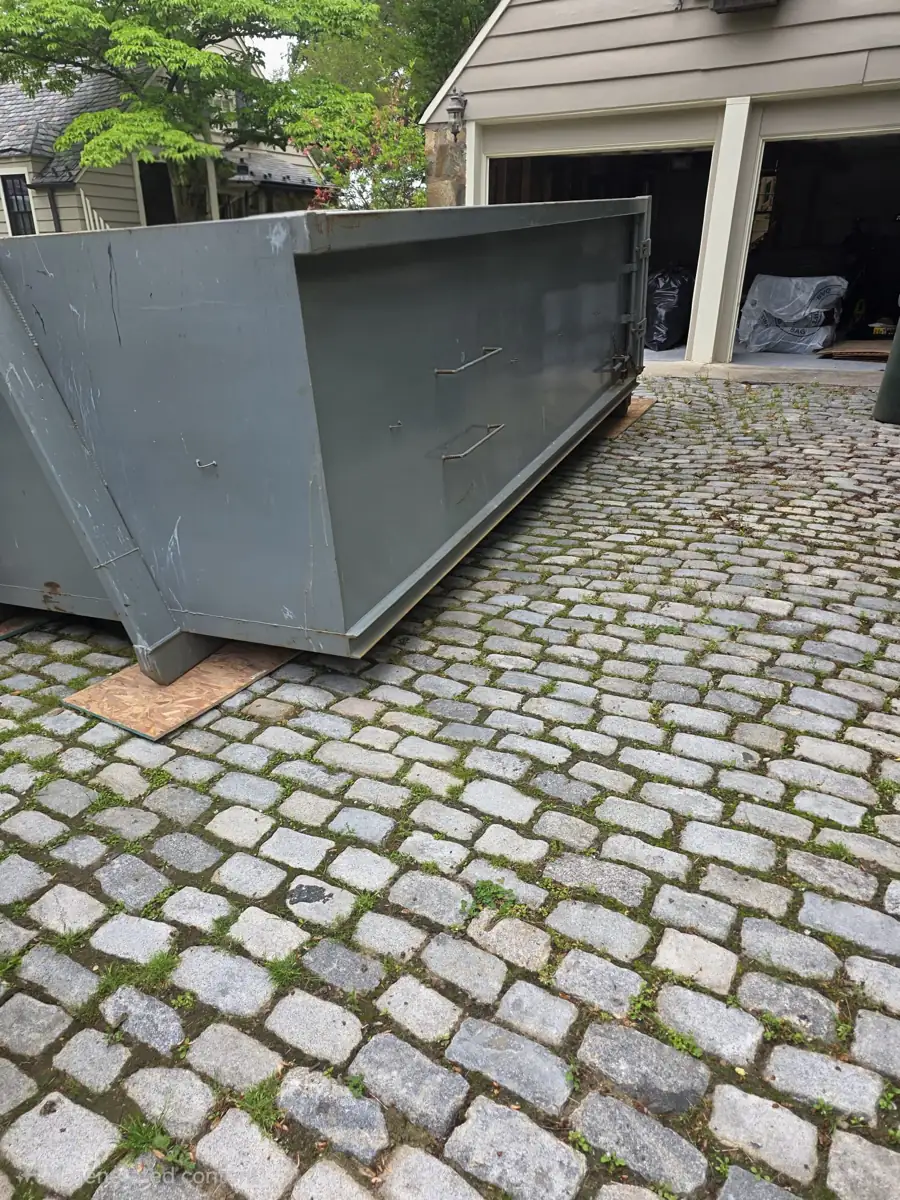 Roll off container on boards over a cobblestone driveway in Rockville, MD