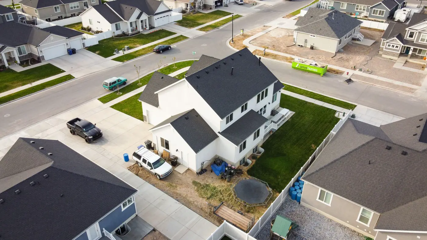 Aerial view of a new suburban subdivision with a green roll off container parked at a home under construction