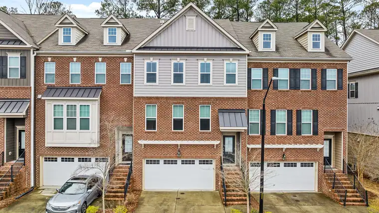 Brick and siding townhomes with garages below and front steps, with a car in one driveway