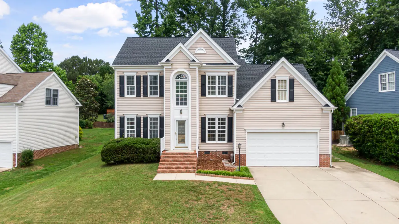 Two-story suburban house with a front-loading garage and concrete driveway between neighboring homes